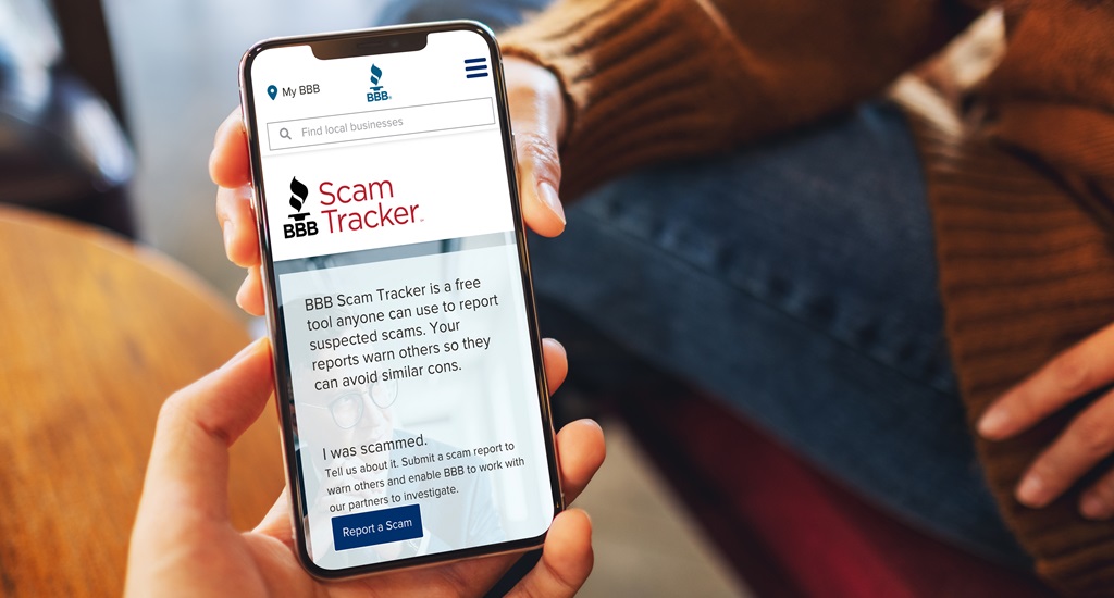 Two hands holding a phone with text on screen explaining what the bbb scam tracker does